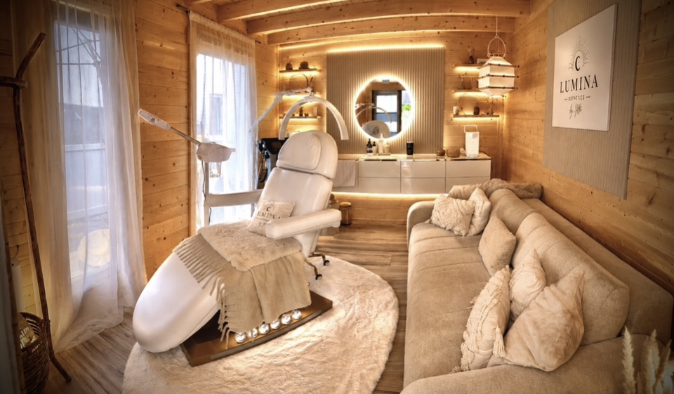 Gemütlicher Lumina-Behandlungsraum mit Holz, warmem Licht, heller Behandlungsliege und Sofa